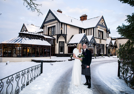 Bride and groom outside hotel during winter with snow on ground and on hotels roof